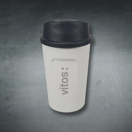 Weißer To-go-Kaffeebecher als Werbeartikel mit graviertem Vitos-Logo und schwarzem Trinkdeckel vor dunklem Hintergrund.
